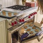 all: Gaby Dalkin taking out a tray of cookies from a stainless steel oven.