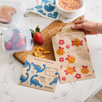 all: paper sandwich and snack bags holding snacks and a 1-cup stasher reusable silicone bowl holding fresh strawberries. 