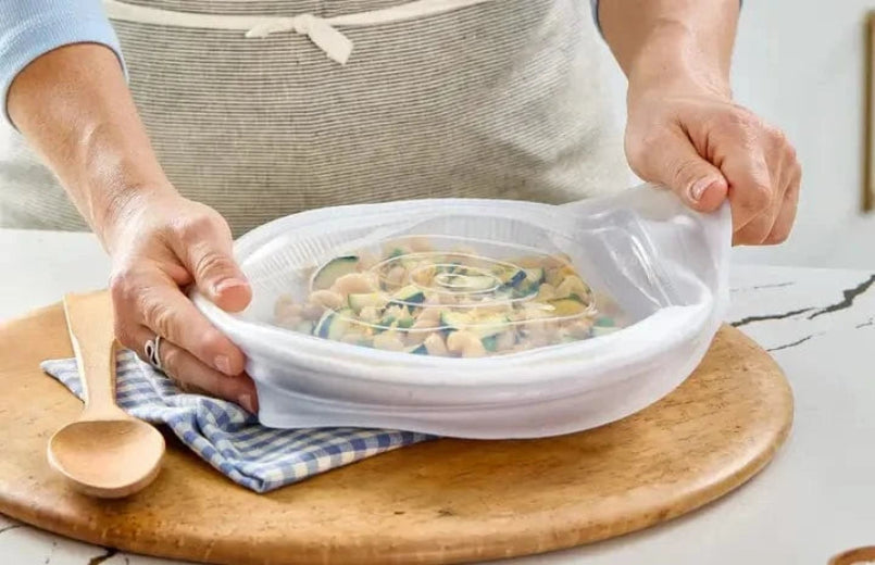 stasher stretch lid being placed over a bowl of pasta salad.