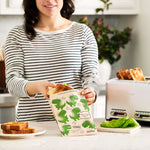 dinosaur: woman putting a sandwich into a paper bag with dinosaur prints on it.