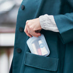 all: travel pocket holding lipsticks being beld in a coat pocket. 