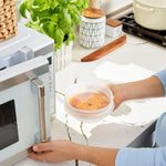 all: small stretch lid covering a bowl of soup and being put in the microwave